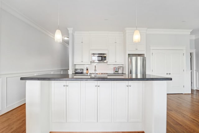 2802 Morrison St Unit 203, Houston, TX 77009 - kitchen featuring appliances with stainless steel finishes, dark countertops, ornamental molding, white cabinets, and an island with sink