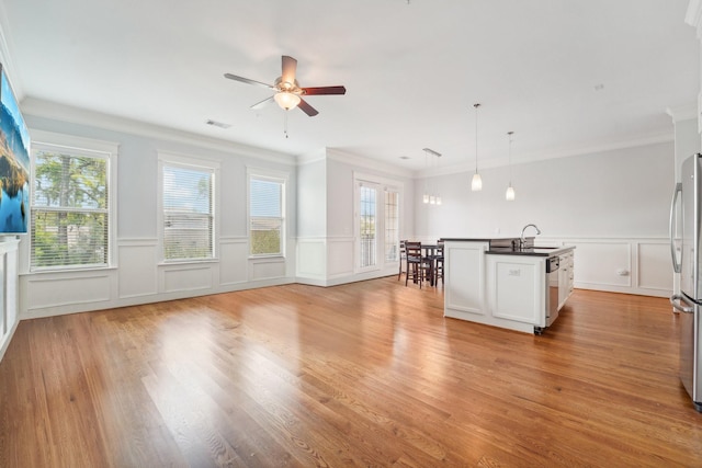 2802 Morrison St Unit 203, Houston, TX 77009 - unfurnished living room featuring plenty of natural light, a decorative wall, ceiling fan, light wood-style flooring, and a wainscoted wall