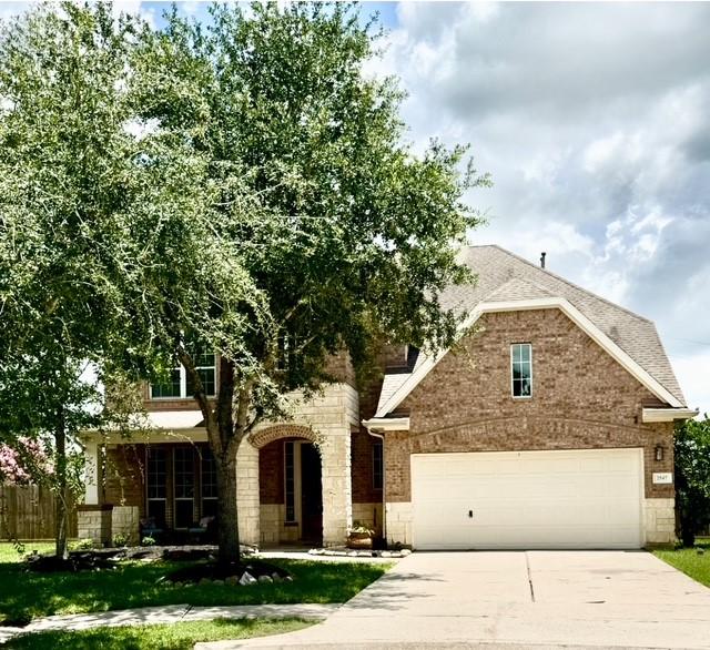 2547 Crystal Shore Dr, Rosharon, TX 77583 - view of front facade featuring concrete driveway, stone siding, an attached garage, brick siding, and a shingled roof
