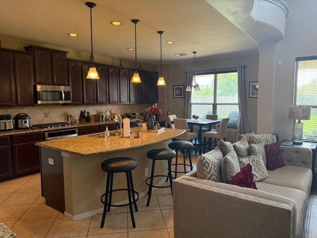 2547 Crystal Shore Dr, Rosharon, TX 77583 - kitchen featuring stainless steel appliances, light tile patterned floors, healthy amount of natural light, a kitchen breakfast bar, and recessed lighting