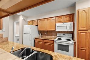 1112 Bering Dr Unit 47, Houston, TX 77057 - kitchen featuring white appliances, light stone counters, and backsplash