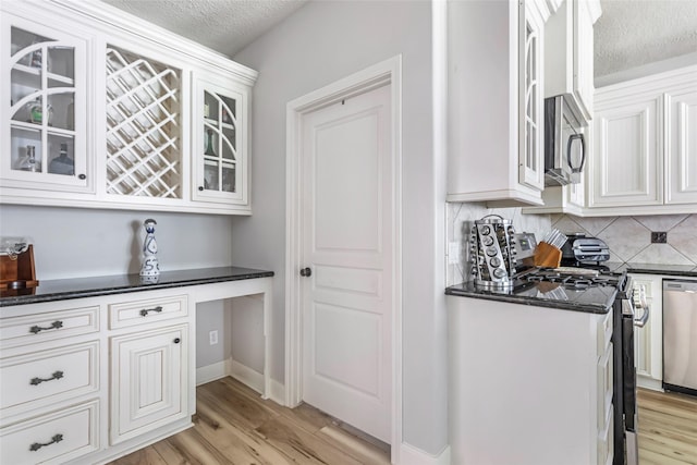 1018 N Commons View Dr, Houston, TX 77336 - kitchen with stainless steel appliances, tasteful backsplash, white cabinetry, light wood-style floors, and a textured ceiling