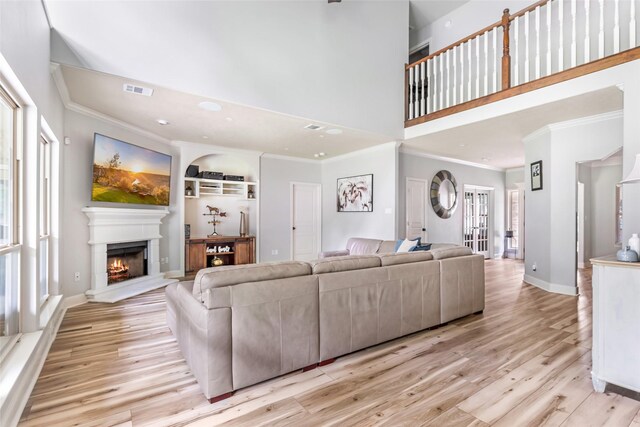 1018 N Commons View Dr, Houston, TX 77336 - living room with crown molding, a lit fireplace, light wood-style floors, a high ceiling, and recessed lighting