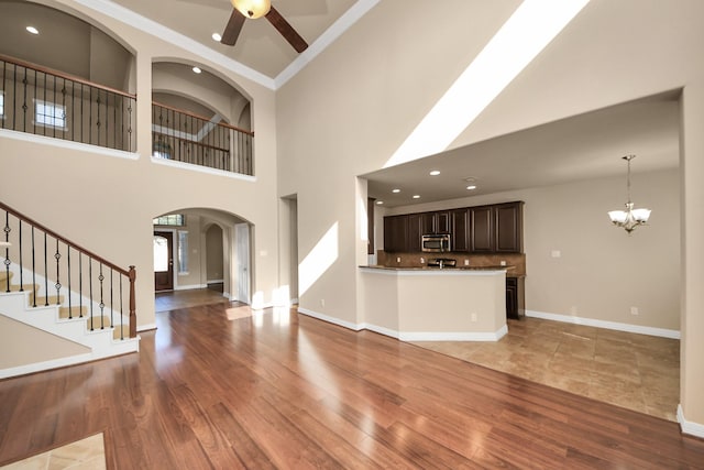 9119 Basin Ridge Ln, Richmond, TX 77407 - unfurnished living room featuring arched walkways, a chandelier, a ceiling fan, light wood-style floors, and a towering ceiling