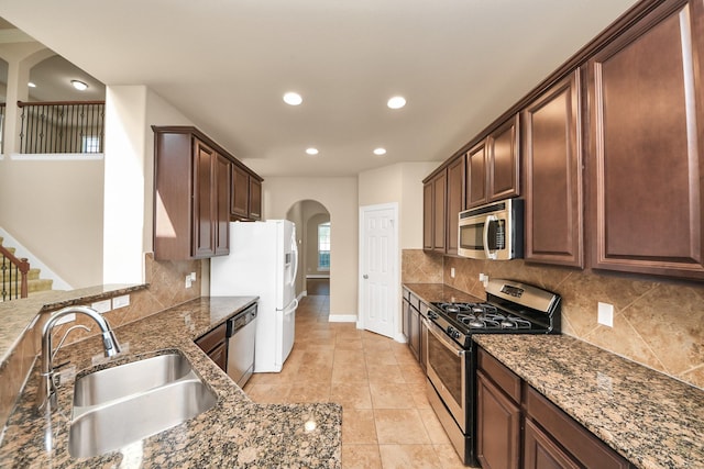 9119 Basin Ridge Ln, Richmond, TX 77407 - kitchen with appliances with stainless steel finishes, arched walkways, dark stone countertops, backsplash, and recessed lighting