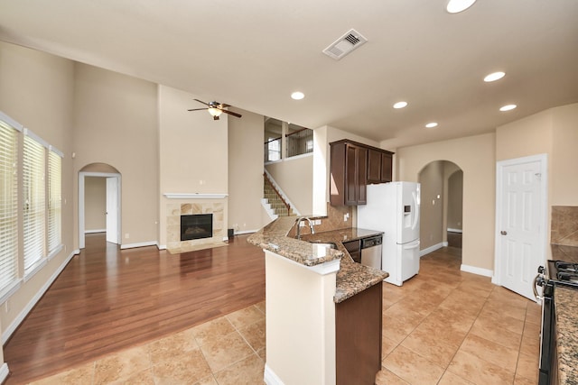 9119 Basin Ridge Ln, Richmond, TX 77407 - kitchen with arched walkways, appliances with stainless steel finishes, a high end fireplace, a peninsula, and dark brown cabinetry