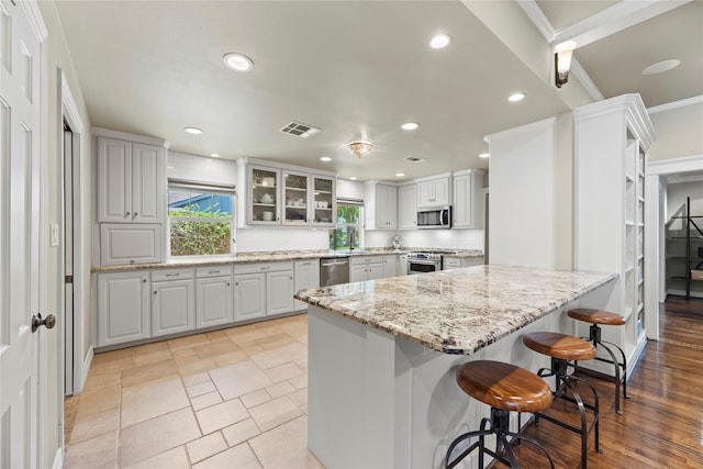 5617 Valerie St, Houston, TX 77081 - kitchen with appliances with stainless steel finishes, a kitchen bar, recessed lighting, crown molding, and light stone countertops