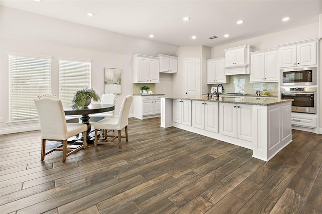 19002 Dublin Bay Blvd, Tomball, TX 77377 - kitchen featuring stainless steel appliances, dark wood-type flooring, white cabinets, decorative backsplash, and recessed lighting