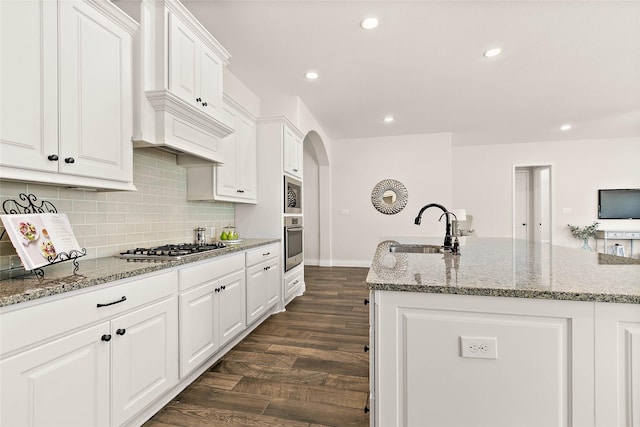 19002 Dublin Bay Blvd, Tomball, TX 77377 - kitchen with appliances with stainless steel finishes, recessed lighting, white cabinetry, arched walkways, and a center island with sink