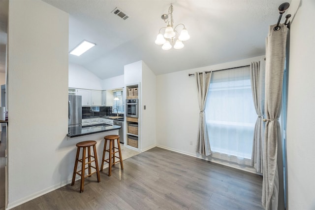 8526 Greenleaf Lake Dr, Houston, TX 77095 - kitchen with stainless steel appliances, dark countertops, vaulted ceiling, wood finished floors, and a peninsula