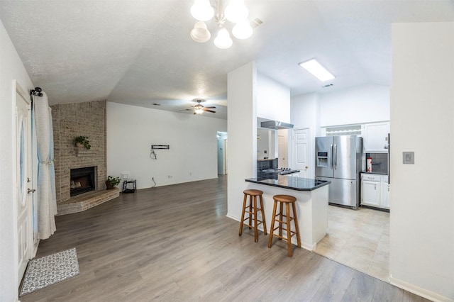 8526 Greenleaf Lake Dr, Houston, TX 77095 - kitchen with stainless steel fridge, lofted ceiling, open floor plan, dark countertops, and a peninsula