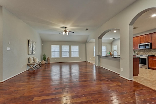 59 Pleasant Point Pl, Spring, TX 77389 - unfurnished living room featuring a ceiling fan, wood-type flooring, lofted ceiling, and arched walkways