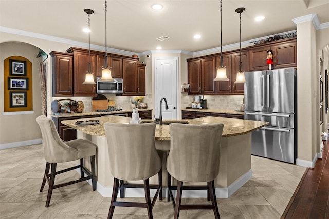 1509 Preserve Ln, Pearland, TX 77089 - kitchen featuring appliances with stainless steel finishes, crown molding, a kitchen breakfast bar, arched walkways, and light stone countertops