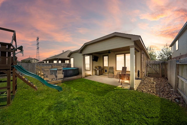 22526 Belmont Cove Ln, Katy, TX 77449 - back of house at dusk featuring a patio, a fenced backyard, a playground, a hot tub, and a ceiling fan