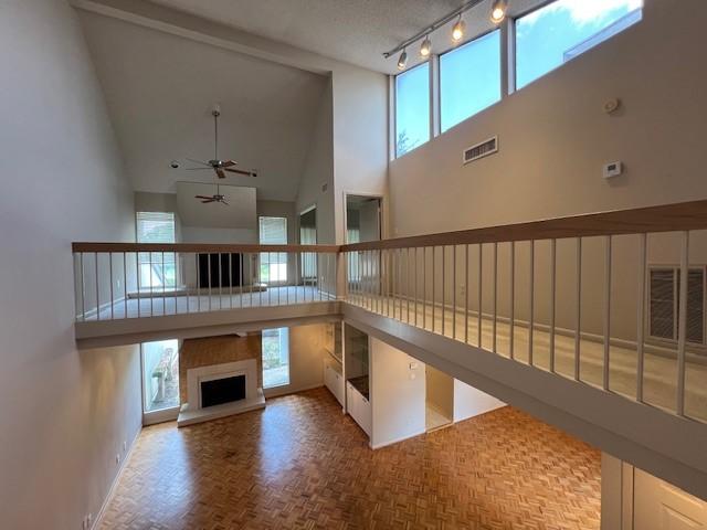 7655 S Braeswood Blvd Unit 8, Houston, TX 77071 - unfurnished living room featuring high vaulted ceiling, a ceiling fan, a fireplace with raised hearth, and rail lighting