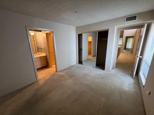 7655 S Braeswood Blvd Unit 8, Houston, TX 77071 - unfurnished bedroom with light carpet, a closet, ensuite bathroom, and a textured ceiling