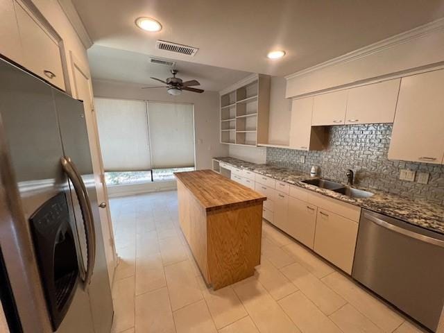 7655 S Braeswood Blvd Unit 8, Houston, TX 77071 - kitchen featuring stainless steel appliances, wooden counters, decorative backsplash, a kitchen island, and white cabinets