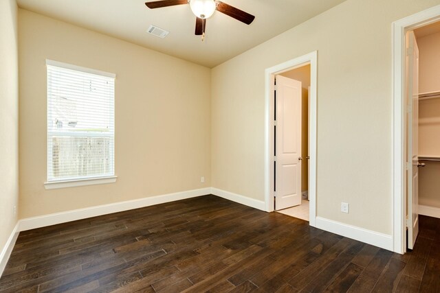 10306 Terra St, Iowa Colony, TX 77583 - unfurnished bedroom featuring dark wood-type flooring, a walk in closet, and a ceiling fan