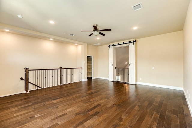 10306 Terra St, Iowa Colony, TX 77583 - empty room with a barn door, ceiling fan, dark wood-type flooring, and recessed lighting