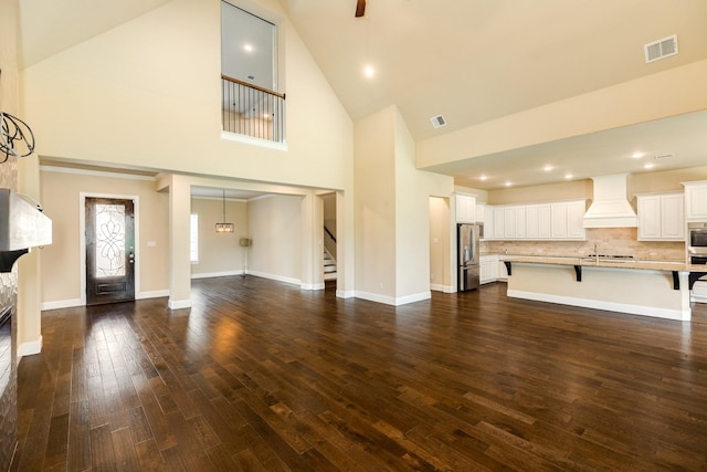 10306 Terra St, Iowa Colony, TX 77583 - unfurnished living room with high vaulted ceiling, stairs, dark wood-style flooring, recessed lighting, and a glass covered fireplace