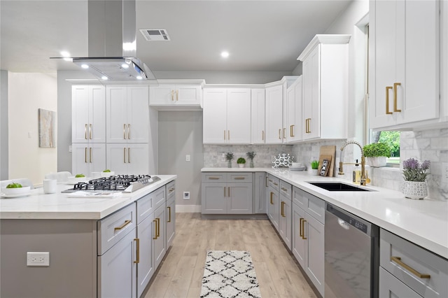 459 Live Oak Rd, Wharton, TX 77488 - kitchen featuring appliances with stainless steel finishes, island exhaust hood, gray cabinetry, decorative backsplash, and light wood-type flooring