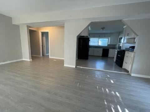 1114 E Pecan St, Angleton, TX 77515 - unfurnished living room featuring baseboards and wood finished floors