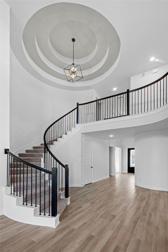 10806 Capella Creek Way, Richmond, TX 77406 - stairs featuring wood finished floors, a towering ceiling, a raised ceiling, and recessed lighting