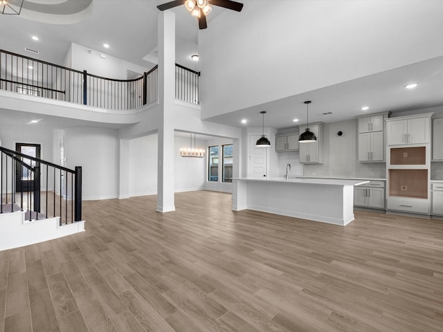 10806 Capella Creek Way, Richmond, TX 77406 - unfurnished living room with a towering ceiling, a ceiling fan, a chandelier, light wood-style floors, and stairway