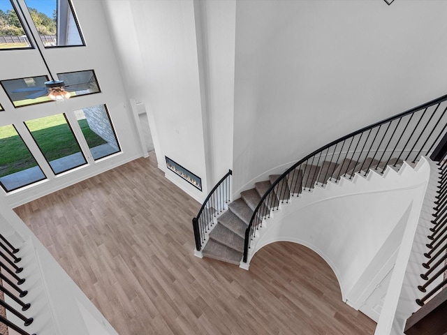 10806 Capella Creek Way, Richmond, TX 77406 - staircase featuring plenty of natural light, wood finished floors, a towering ceiling, a glass covered fireplace, and a ceiling fan