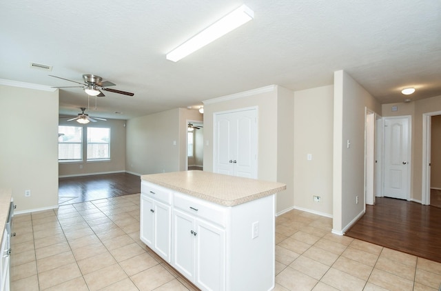 19826 Seagler Glen Ln, Katy, TX 77449 - kitchen featuring a ceiling fan, light tile patterned floors, light countertops, a kitchen island, and crown molding