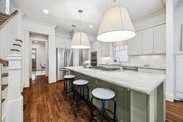 1017 Waverly St Unit B, Houston, TX 77008 - kitchen featuring appliances with stainless steel finishes, crown molding, a center island, decorative backsplash, and a kitchen bar