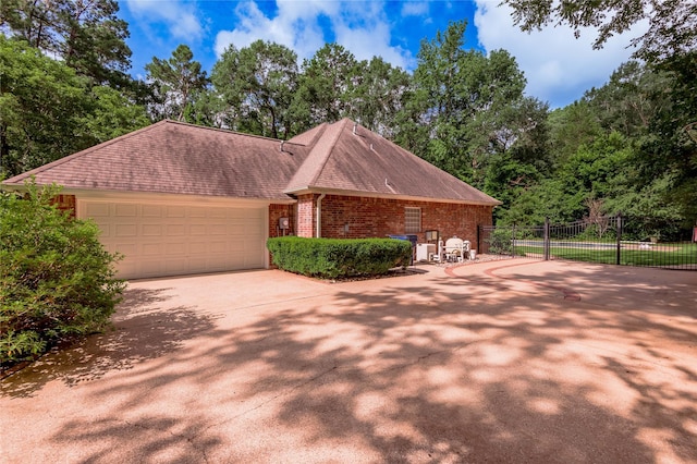 426 County Road 222, Nacogdoches, TX 75965 - view of front of house with brick siding, concrete driveway, a garage, a shingled roof, and view of wooded area
