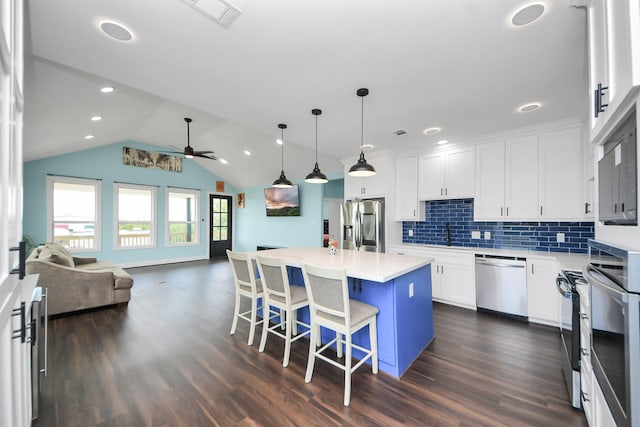 1309 24th St, Dickinson, TX 77539 - kitchen featuring appliances with stainless steel finishes, open floor plan, ceiling fan, a kitchen island, and dark wood-style floors