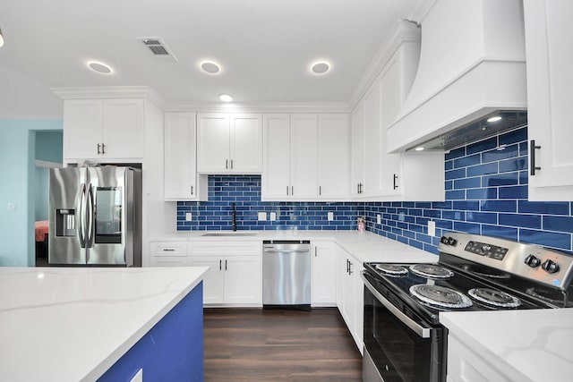 1309 24th St, Dickinson, TX 77539 - kitchen featuring stainless steel appliances, custom range hood, dark wood-style flooring, white cabinetry, and backsplash