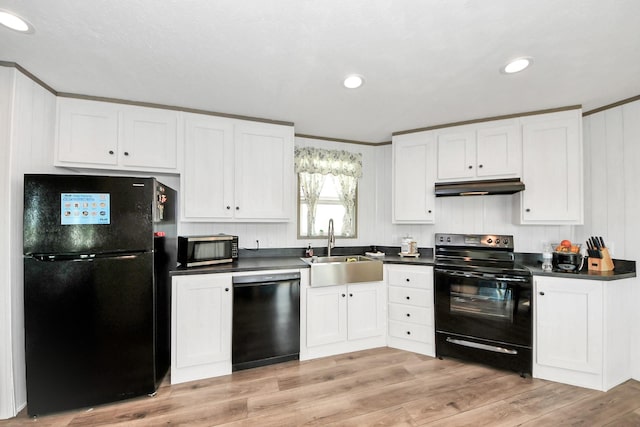 1309 24th St, Dickinson, TX 77539 - kitchen with black appliances, under cabinet range hood, white cabinets, dark countertops, and light wood-type flooring
