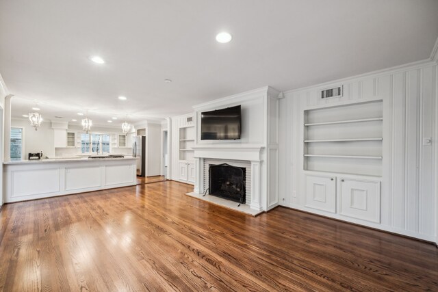 5659 Chevy Chase Dr, Houston, TX 77056 - unfurnished living room with a brick fireplace, built in shelves, recessed lighting, a chandelier, and wood finished floors