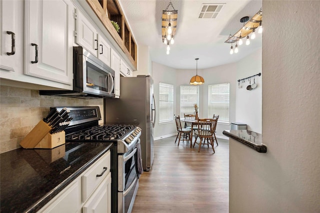 20315 Maple Village Dr, Cypress, TX 77433 - kitchen featuring appliances with stainless steel finishes, tasteful backsplash, white cabinetry, wood finished floors, and dark stone counters
