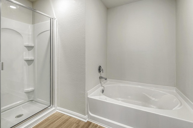 8219 Blooming Meadow Dr, Houston, TX 77016 - bathroom with wood finished floors, a stall shower, a garden tub, and a textured wall