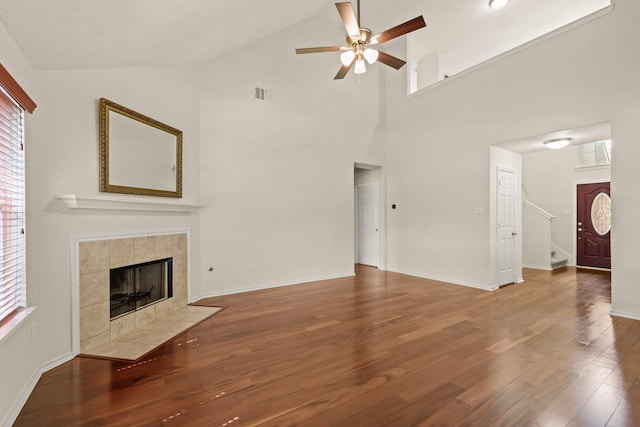 16210 Bloom Meadow Trl, Cypress, TX 77433 - unfurnished living room with ceiling fan, wood finished floors, stairs, high vaulted ceiling, and a tiled fireplace