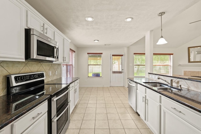 16210 Bloom Meadow Trl, Cypress, TX 77433 - kitchen with appliances with stainless steel finishes, a textured ceiling, tasteful backsplash, healthy amount of natural light, and white cabinetry
