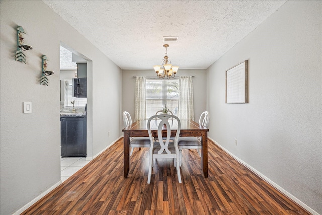 2310 Parkview Dr, Pearland, TX 77581 - dining space featuring a chandelier, light wood-style floors, a textured ceiling, and a textured wall