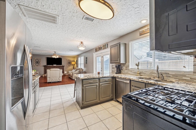 2310 Parkview Dr, Pearland, TX 77581 - kitchen with appliances with stainless steel finishes, a peninsula, backsplash, light tile patterned floors, and a textured ceiling