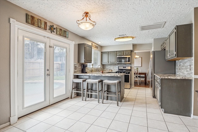 2310 Parkview Dr, Pearland, TX 77581 - kitchen featuring appliances with stainless steel finishes, a peninsula, a textured ceiling, tasteful backsplash, and french doors