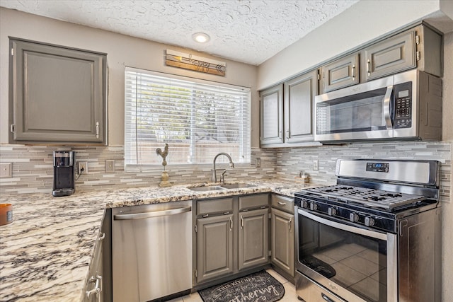 2310 Parkview Dr, Pearland, TX 77581 - kitchen with appliances with stainless steel finishes, gray cabinetry, a textured ceiling, tasteful backsplash, and light stone counters