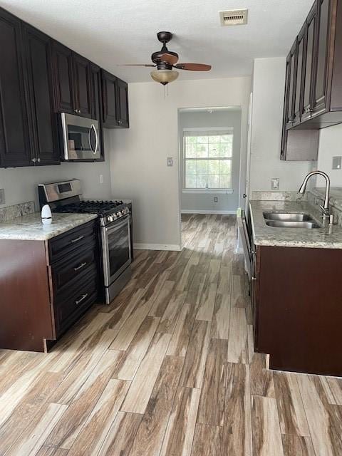 12326 Garden Gale Ln, Houston, TX 77044 - kitchen featuring stainless steel appliances, ceiling fan, light wood finished floors, and light stone counters
