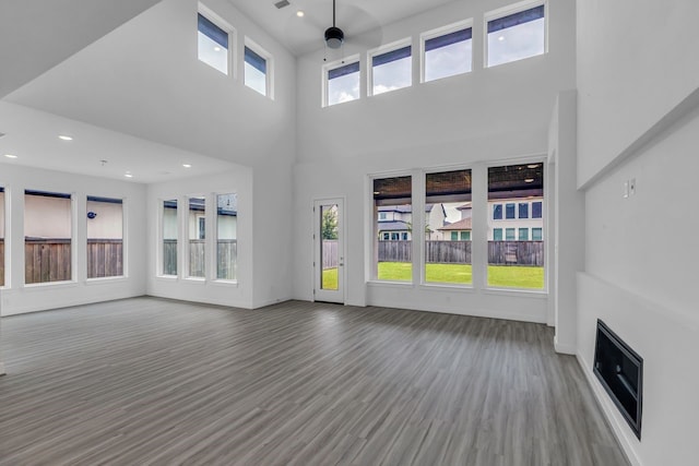 15643 Thirsty Horse Trl, Cypress, TX 77433 - unfurnished living room featuring plenty of natural light, wood finished floors, recessed lighting, and a towering ceiling