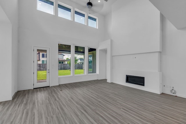 15643 Thirsty Horse Trl, Cypress, TX 77433 - unfurnished living room with a glass covered fireplace, a high ceiling, and wood finished floors