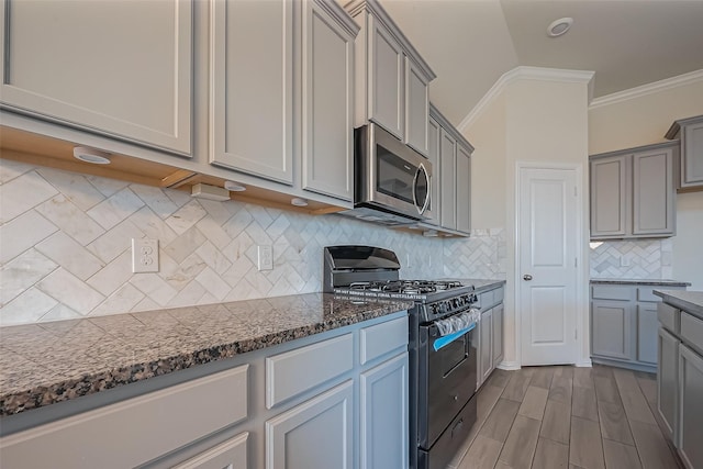 1111 Teamriddle Way, Richmond, TX 77406 - kitchen with black gas range, stainless steel microwave, gray cabinetry, crown molding, and dark stone countertops
