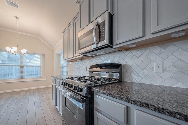 1111 Teamriddle Way, Richmond, TX 77406 - kitchen featuring appliances with stainless steel finishes, gray cabinetry, vaulted ceiling, decorative backsplash, and a chandelier