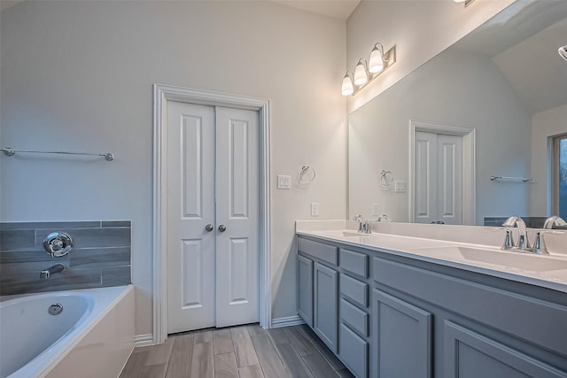 1111 Teamriddle Way, Richmond, TX 77406 - bathroom with double vanity, a garden tub, wood finished floors, and lofted ceiling